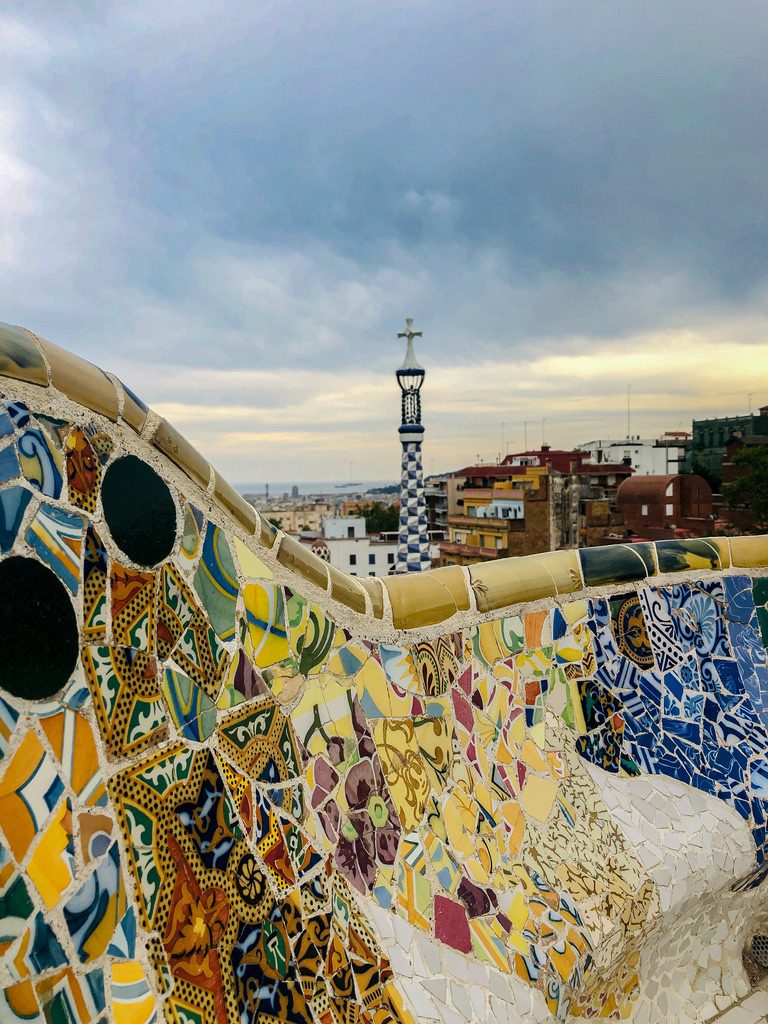 Park Guell z ławkami i drzewami.
